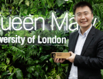 Dr Yuanwei Liu with his Early Career Researcher prize, standing in front of a green wall