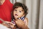 A toddler recieves a vaccine in his arm