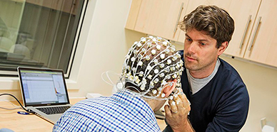Man fitting an EEG cap onto a subject