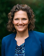 Frauke Nitschke wearing a blue top and standing in front of shrubbery