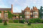 The outside of Tylney Hall. It is a red bricked manor house with wisteria growing up the walls.