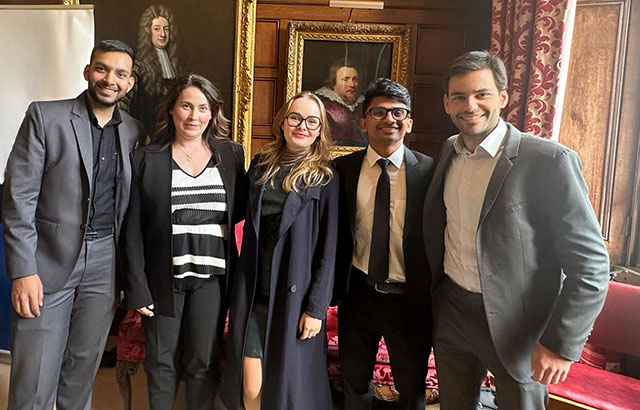 Karan Abhaykumar Parmar, Dr Maria Fanou, Daria Korniienko, Minul Muhamdiramge and João Gabriel Volasco Rodrigues standing in front of a panelled wall with portraits.