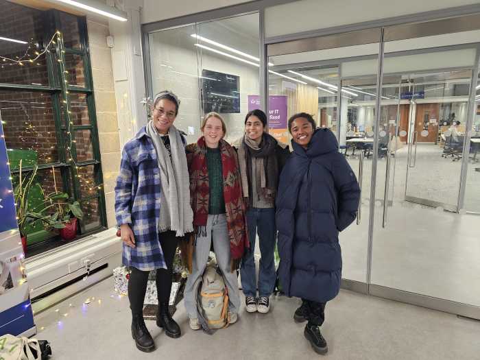 Four dancers from Chisenhale Dance Space pose outside the entrance to QM Mile End Library