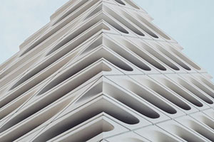 The façade of a white geometric building with lots of holes.