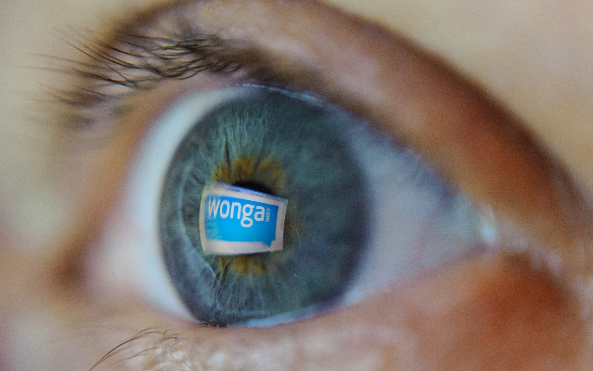 A close up of a person's blue eye with a Wonga logo reflected in it