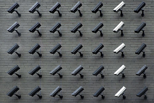 Lines of security cameras arranged on a brick wall