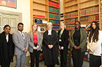 A group photo of Chelsea and Rodney with QMLAC support staff and Right Hon Mrs Justice Stacey standing in from of book shelves.