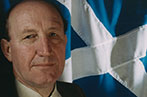 Neil MacCormick with the Scottish flag behind him.