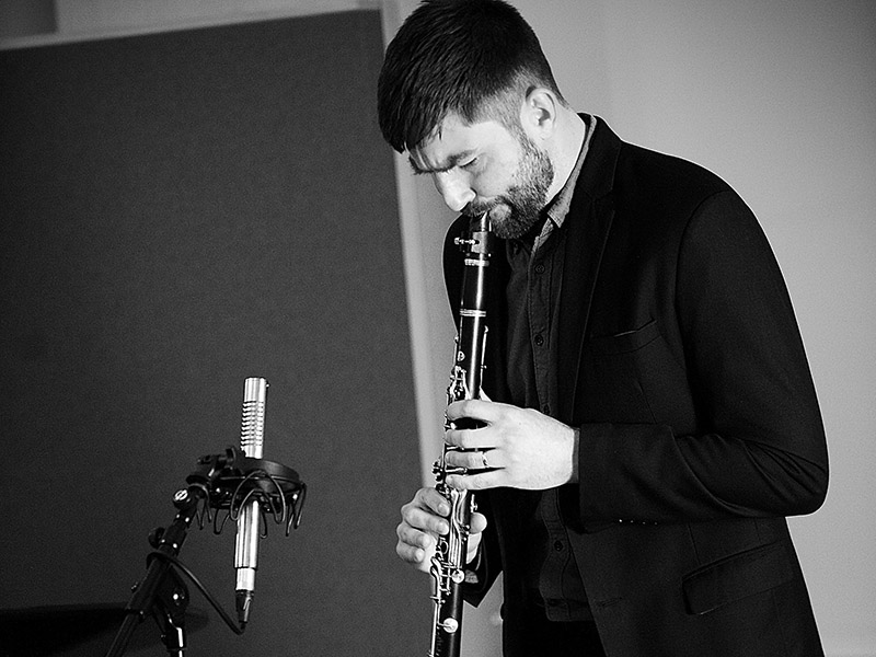 A black and white photo of a man playing a clarinet into a microphone