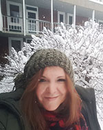 Dr Delfi Nieto-Isabel. She is wearing a wooly hat and coat, and standing in front of a snowy tree.