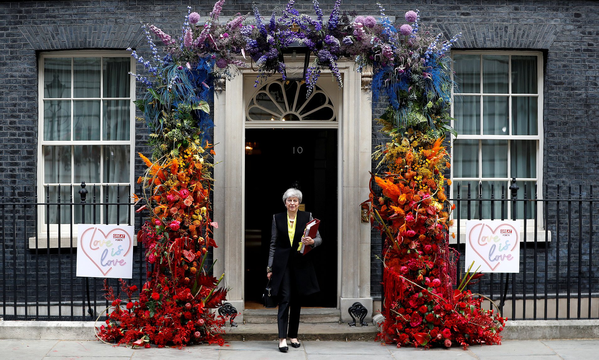 Downing Street, UK. 3rd July 2019. British Prime Minister, Theresa May leaves No 10 Downing Street for Prime Ministers Questions, through an arch of flowers there to celebrate Pride in London. Credit: Thomas Bowles/Alamy Live News