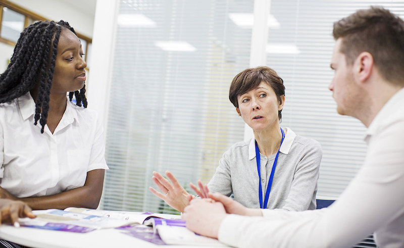 Three staff members talking around a table