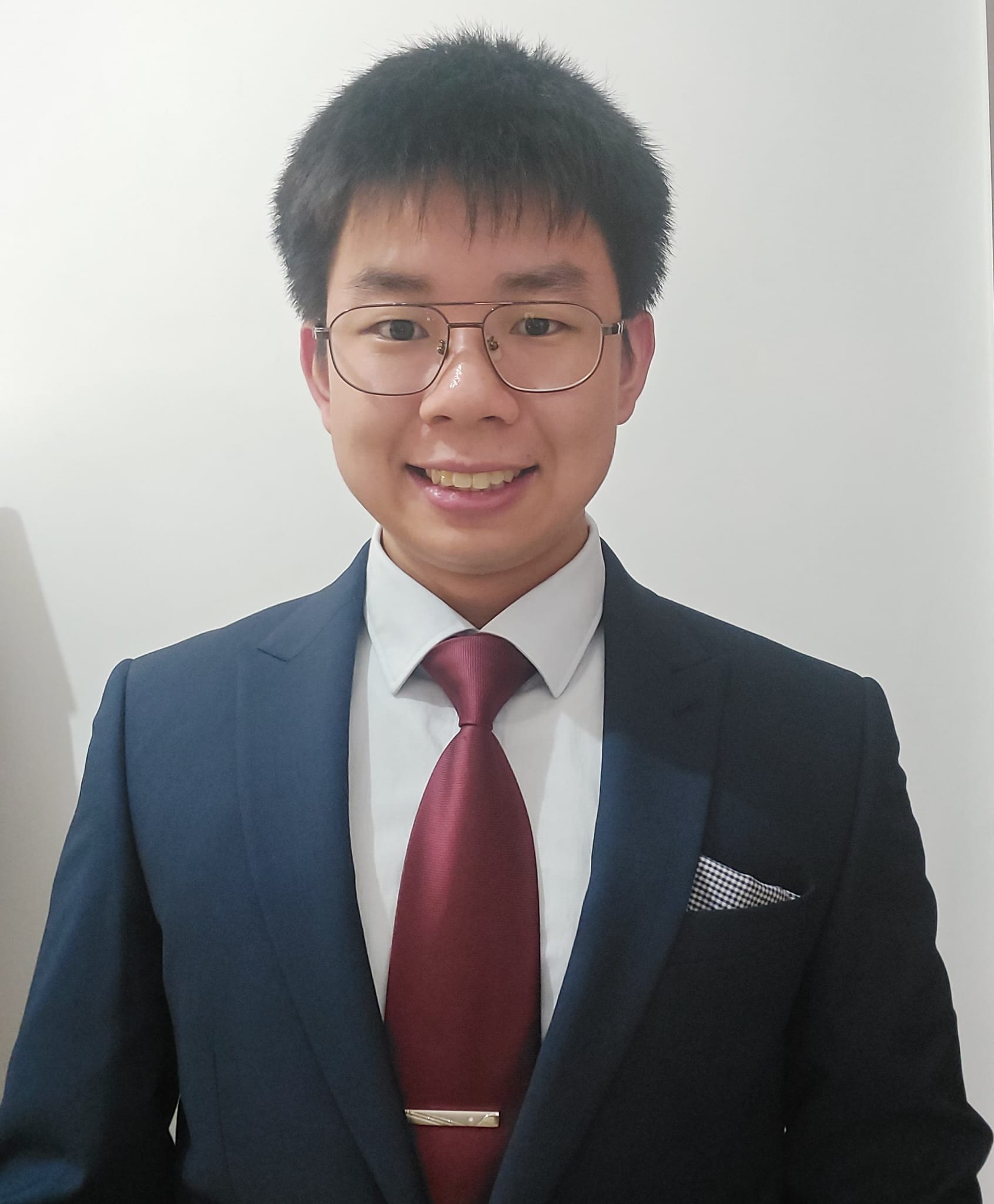 Adams Lau wearing a blue suit and burgundy tie