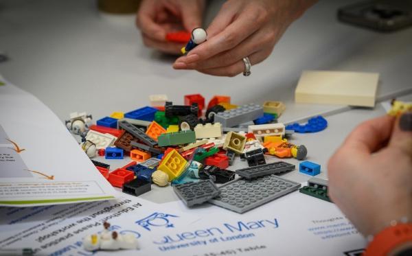 A pile of Lego with two hands building